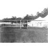 Frank Coffyn (right) and Duval La Chapelle posing in a Wright aircraft in front of tents.