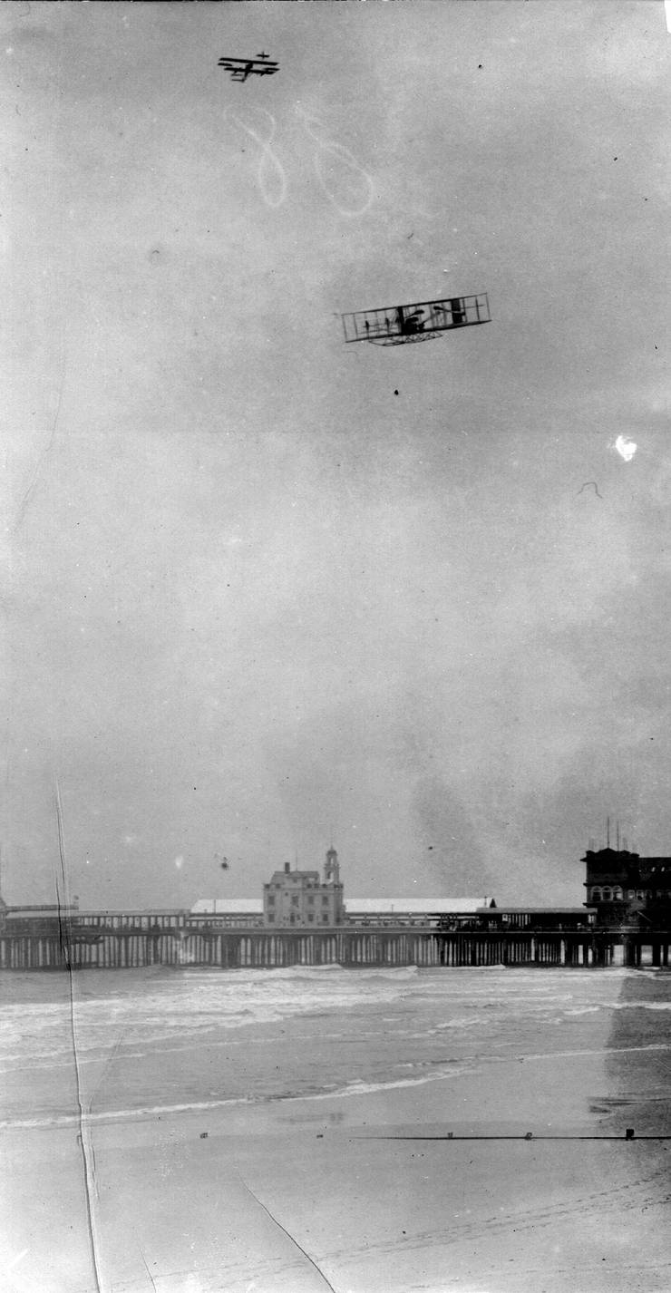 Walter Brookins descending without power after altitude record flight; Glenn Curtiss in flight behind him.