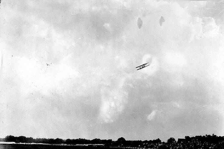 Wright transitional in flight over a crowd.