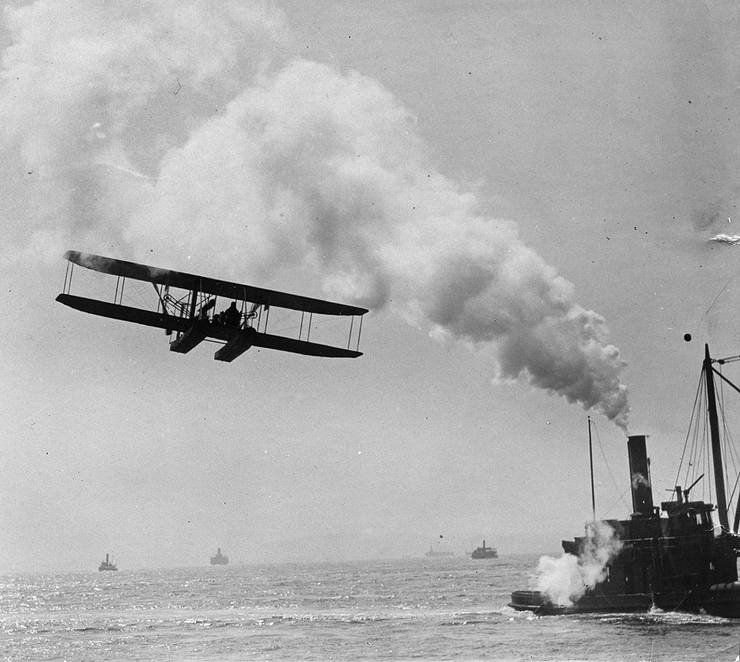 Frank Coffyn flying near a tugboat, New York Harbor.