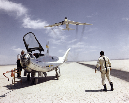 HL-10 on lakebed with B-52 flyby