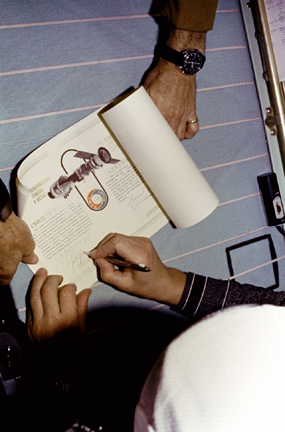 Cosmonaut Kubasov adds his name on the Soviet side of the official joint certificate